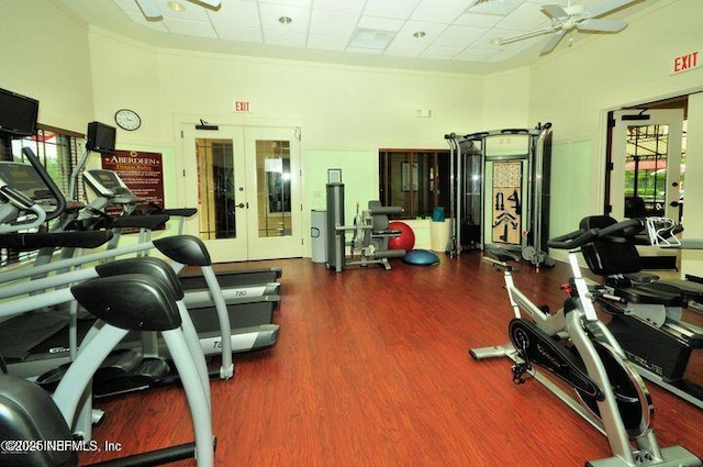 workout area featuring wood finished floors, a towering ceiling, french doors, crown molding, and ceiling fan