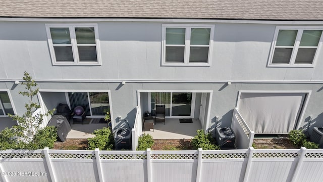 view of front of house with a patio area, roof with shingles, and a fenced backyard