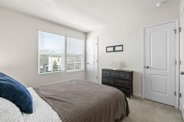 bedroom with baseboards, a textured ceiling, and light colored carpet