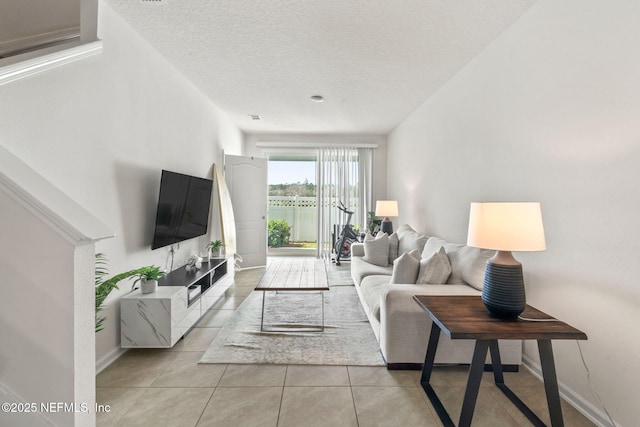 living room with light tile patterned floors, baseboards, and a textured ceiling