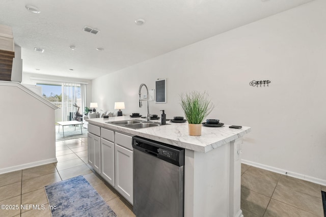 kitchen featuring light tile patterned floors, a sink, visible vents, dishwasher, and a center island with sink