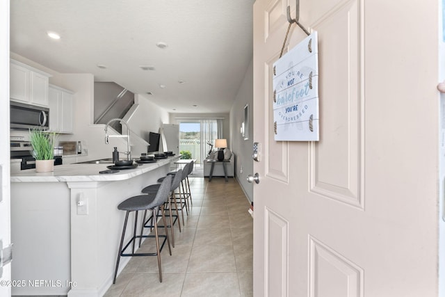 kitchen with light tile patterned floors, visible vents, a breakfast bar, stainless steel appliances, and a sink