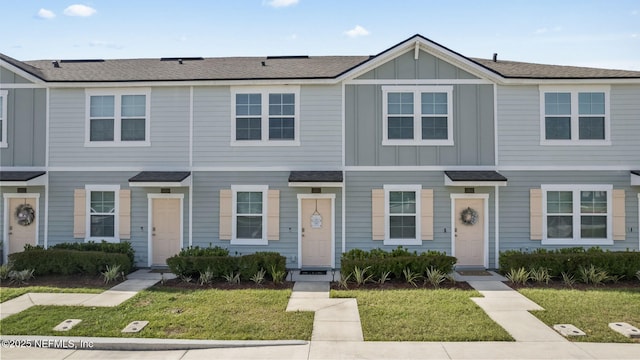 townhome / multi-family property featuring roof with shingles, board and batten siding, and a front yard