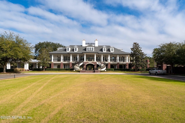 view of front of house with a front yard, a chimney, and a balcony