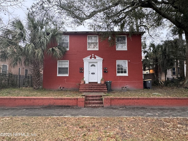 view of front of property with brick siding and fence