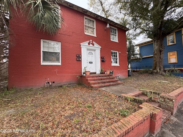 view of front of house with crawl space, entry steps, and brick siding