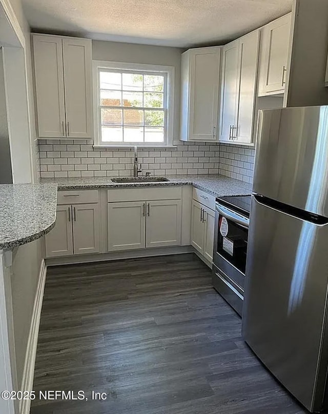 kitchen with white cabinetry, appliances with stainless steel finishes, light stone counters, and a sink