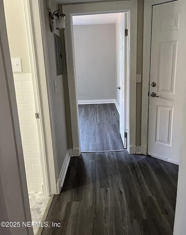 corridor with dark wood-style flooring and baseboards