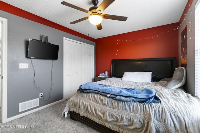 carpeted bedroom featuring a closet, visible vents, a textured ceiling, and a ceiling fan