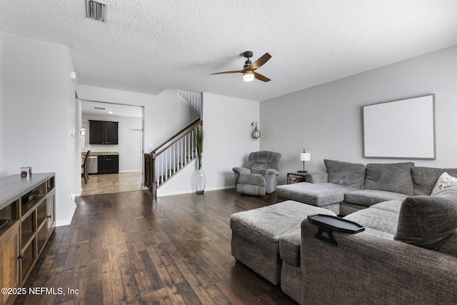 living area with visible vents, a ceiling fan, dark wood finished floors, stairway, and baseboards