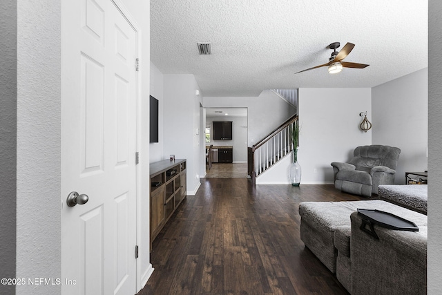 living area featuring visible vents, a ceiling fan, a textured ceiling, dark wood-style floors, and stairs