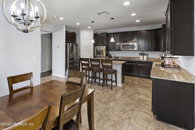 kitchen featuring a center island, light stone countertops, a breakfast bar, a notable chandelier, and stainless steel appliances