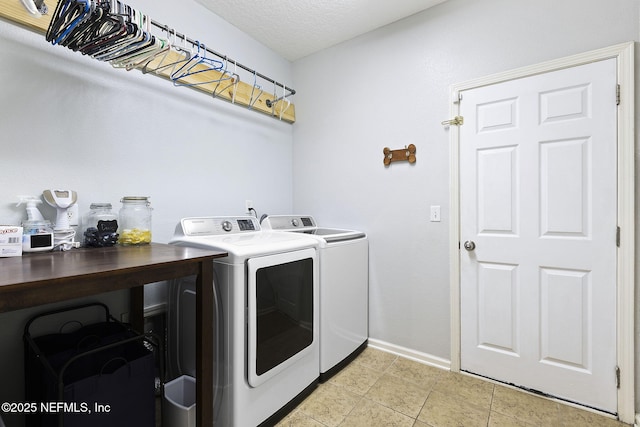 clothes washing area featuring independent washer and dryer, a textured ceiling, light tile patterned floors, baseboards, and laundry area