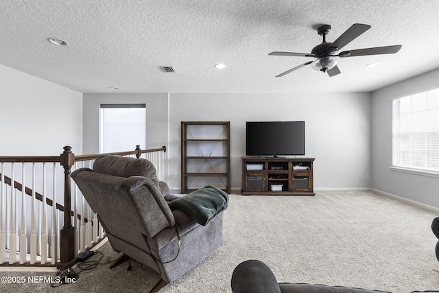 living room with visible vents, baseboards, carpet floors, a textured ceiling, and a ceiling fan