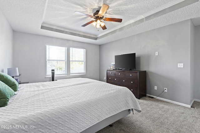 bedroom featuring light carpet, a textured ceiling, baseboards, and a tray ceiling