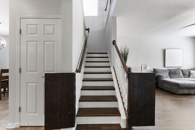 stairs with a textured ceiling and wood finished floors