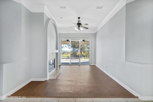 unfurnished living room featuring visible vents, crown molding, baseboards, and a premium fireplace