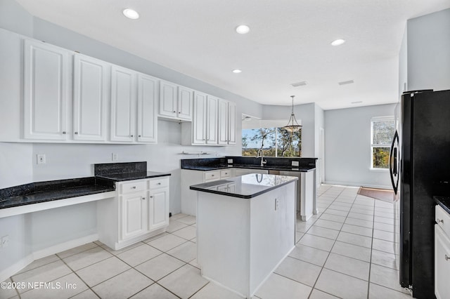 kitchen with light tile patterned flooring, a kitchen island, freestanding refrigerator, and white cabinets