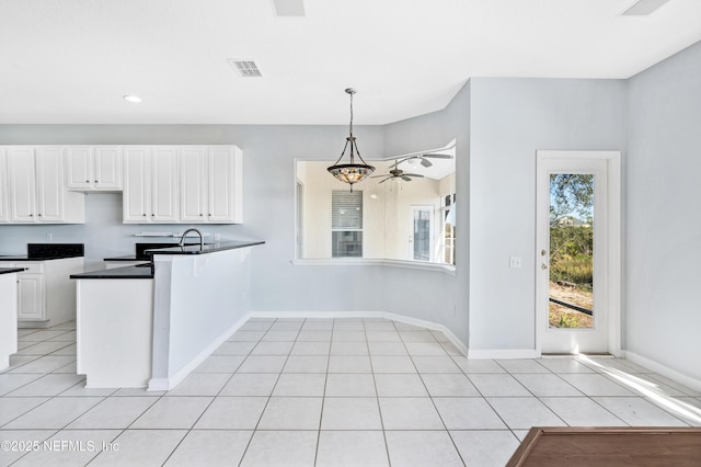 kitchen with visible vents, white cabinets, dark countertops, a peninsula, and light tile patterned flooring