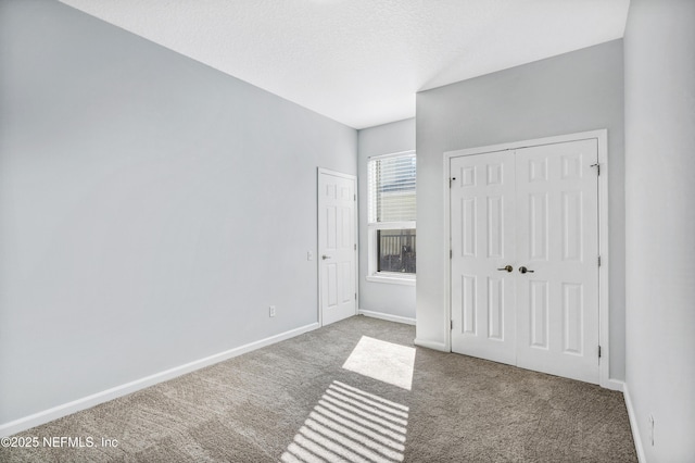 unfurnished bedroom featuring a textured ceiling, a closet, carpet flooring, and baseboards