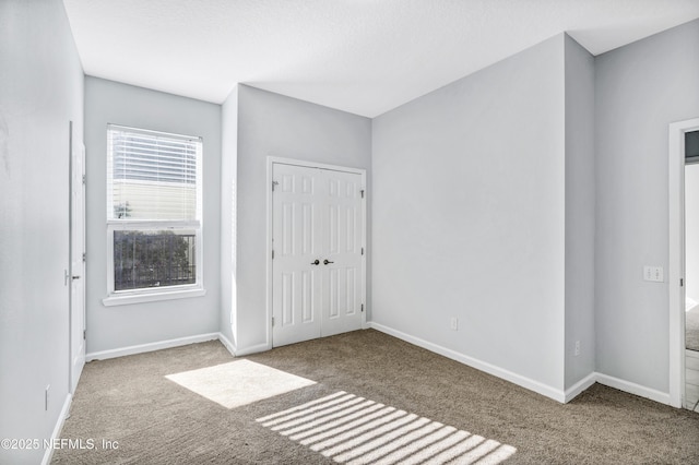 unfurnished bedroom featuring carpet, baseboards, and a closet