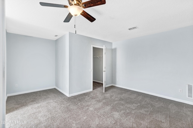 unfurnished bedroom with a spacious closet, carpet, visible vents, and baseboards