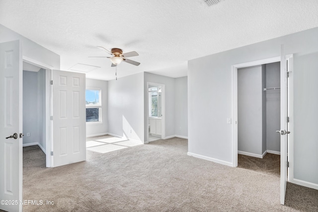 unfurnished bedroom featuring a walk in closet, a textured ceiling, and carpet