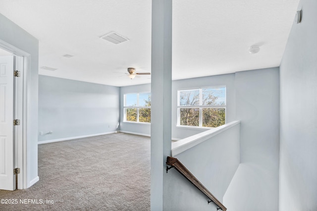 carpeted empty room with a ceiling fan, visible vents, and baseboards