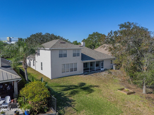 back of property featuring roof with shingles, a lawn, a vegetable garden, and stucco siding