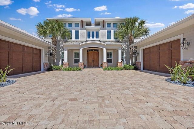 view of front facade featuring a standing seam roof, decorative driveway, and metal roof