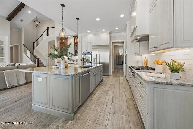 kitchen featuring backsplash, gray cabinetry, open floor plan, light wood-type flooring, and stainless steel appliances