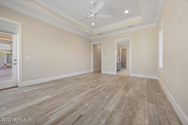 interior space with light wood-style flooring, a tray ceiling, crown molding, baseboards, and ceiling fan