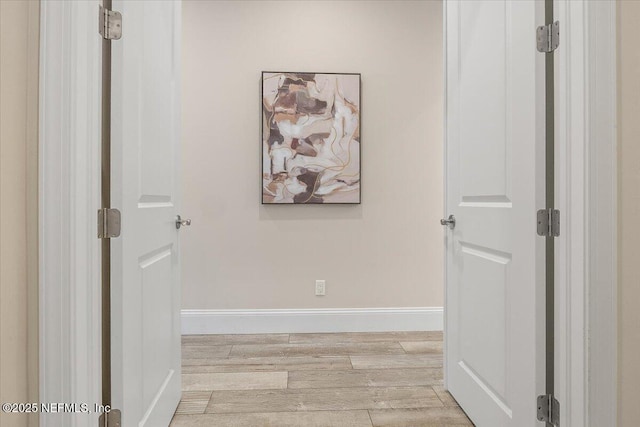 hallway featuring light wood-style flooring and baseboards