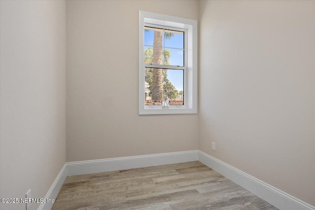 unfurnished room with baseboards and light wood-style flooring