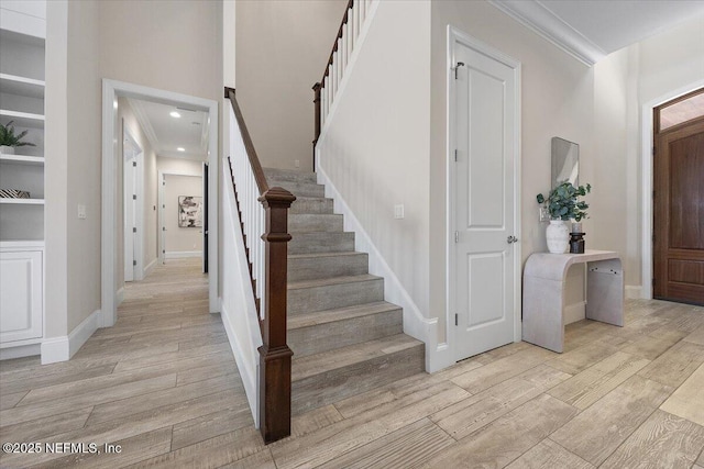 foyer entrance featuring baseboards, stairs, light wood-type flooring, ornamental molding, and recessed lighting