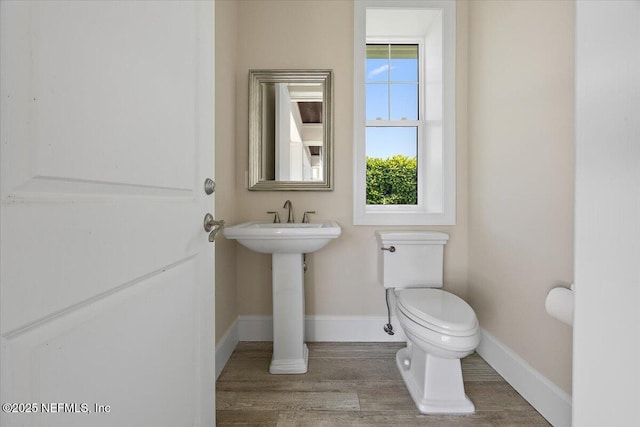 bathroom featuring toilet, wood finished floors, and baseboards