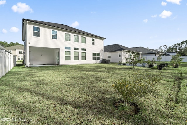 rear view of house featuring a lawn and fence