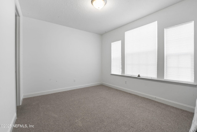 spare room featuring carpet, a textured ceiling, and baseboards