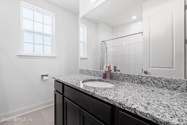 bathroom featuring vanity, baseboards, tiled shower, and tile patterned floors