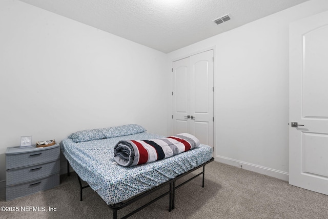 bedroom with baseboards, visible vents, carpet, a textured ceiling, and a closet