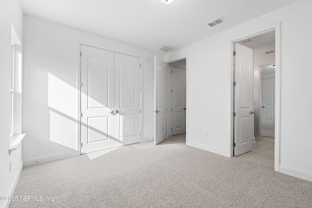 unfurnished bedroom featuring a closet, carpet flooring, visible vents, and baseboards