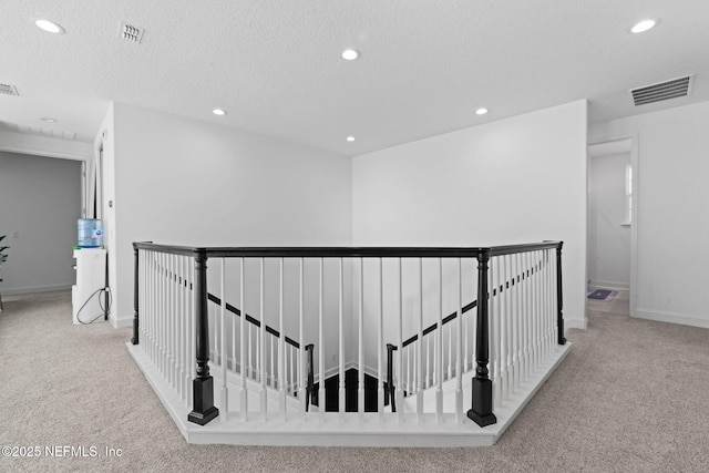 hallway with recessed lighting, carpet flooring, visible vents, and an upstairs landing