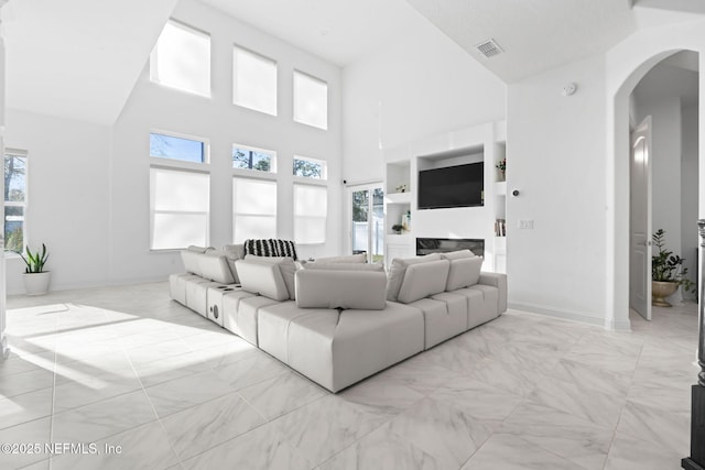 living room featuring arched walkways, marble finish floor, a towering ceiling, and visible vents