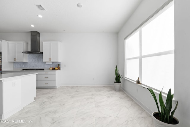 kitchen with black cooktop, visible vents, baseboards, wall chimney exhaust hood, and tasteful backsplash