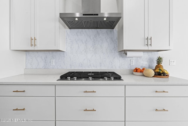 kitchen with white cabinetry, wall chimney exhaust hood, stainless steel gas cooktop, and decorative backsplash