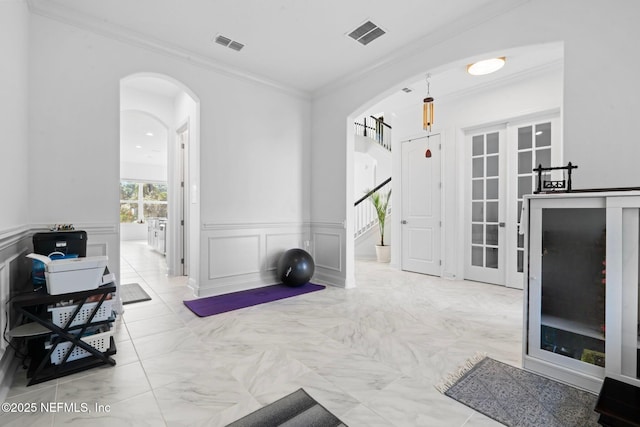 workout room with ornamental molding, arched walkways, a wainscoted wall, and visible vents