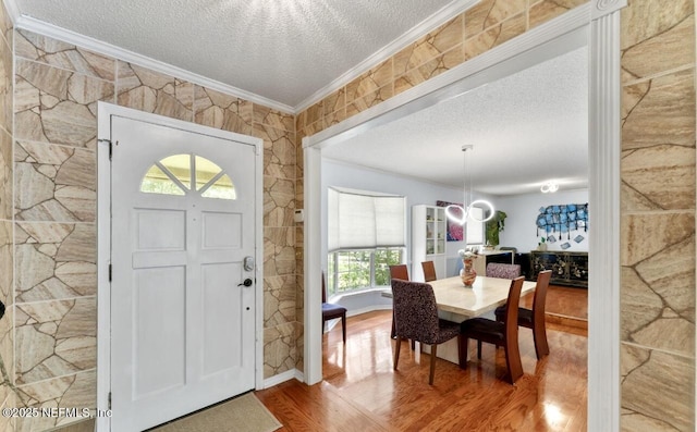 entrance foyer featuring a textured ceiling, ornamental molding, wood finished floors, and an inviting chandelier