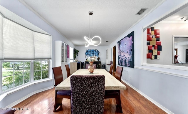 dining space featuring crown molding, visible vents, wood finished floors, a chandelier, and baseboards