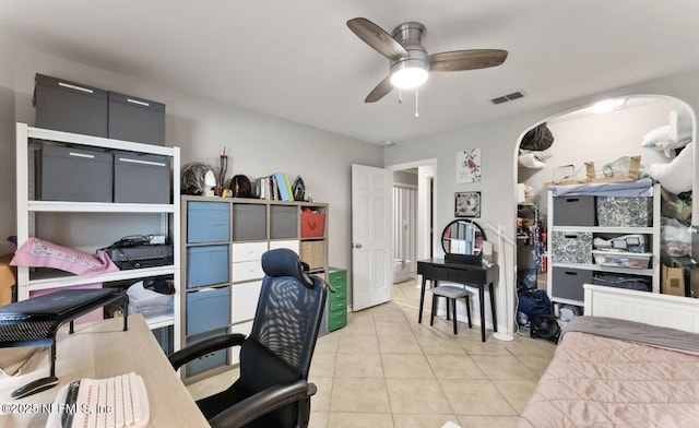 home office with visible vents, arched walkways, a ceiling fan, and light tile patterned flooring