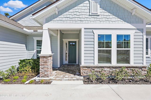 property entrance with stone siding and a shingled roof